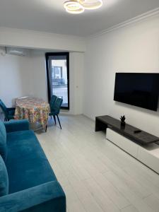 Una sala de estar con un sofá azul y un televisor de pantalla plana. en VIRGO APARTAMENTS LAKE VIEW, en Mamaia