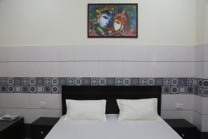 a bed with two pillows and a painting above it at Luxury Room with 1 Double Bed in Haridwār