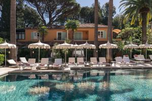 a pool with chairs and umbrellas and a building at La Bastide de Saint Tropez in Saint-Tropez