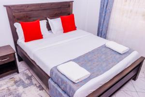 una camera da letto con un letto con cuscini rossi e bianchi di The pine 1 bedroom house California plaza a Nanyuki