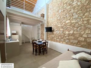 Habitación con mesa y pared de piedra. en Tenute Plaia Agriturismo en Scopello