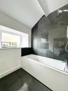 Un baño con bañera blanca y ventana. en The Birketts Inn, 4 - Bed, Sleeps 8, Pets Welcome, en Ulverston