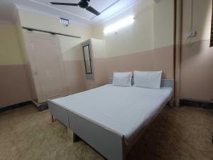 a bedroom with a large bed with white sheets at Hotel O Nitya in Ayodhya +8 photos