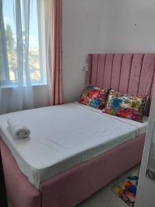 a bed with a pink headboard and pillows on it at Khalisee homes 2 bedroom apartment in Bamburi in Mombasa