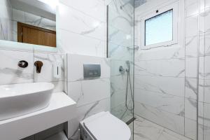 a white bathroom with a sink and a shower at Fotini Studios in Chrysi Ammoudia +14 photos