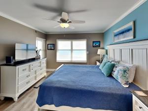 a bedroom with a blue bed and a ceiling fan at Sea Winds 904 in Ormond Beach