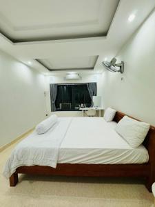 a bedroom with a bed with white sheets and a window at Vika Homestay in Ho Chi Minh City