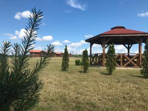 a wooden gazebo in a field with trees at Domki na Wzgórzu in Ryn