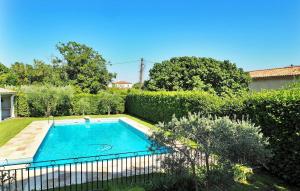 ein Pool in einem Garten neben einer Hecke in der Unterkunft Villa Les Sapins in Moulès