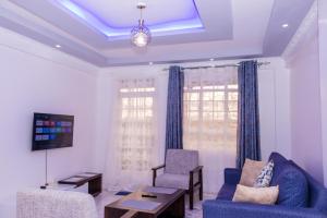 a living room with a blue couch and a table at The pine 1 bedroom house California plaza in Nanyuki
