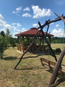 a swing set in a field with a gazebo at Domki na Wzgórzu in Ryn