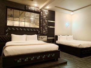 a bedroom with two beds and a window at MZ Hotel and Restaurant Sukkur in Kalar Goth