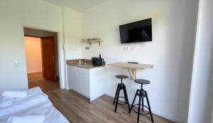 a room with a bed and a small kitchen with stools at Hotel Buchberg - Moderne Design-Apartments in Bermatingen