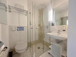 a bathroom with a toilet and a sink and a shower at Hotel Buchberg - Moderne Apartments in Bermatingen