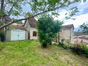 une maison avec un garage blanc dans une cour dans l'établissement Maison coeur de St-Cirq-Lapopie Charme Jardin Clim, à Saint-Cirq-Lapopie