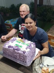 un hombre y una mujer sosteniendo un pastel de cumpleaños en CASA MIA INN en Dauis