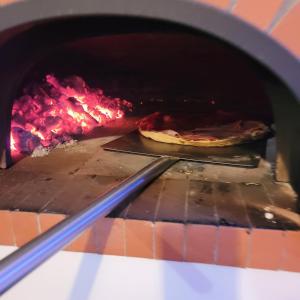 una pizza está siendo cocinada en un horno en Domaine de la Charrière sur 63 ares - 8 pers grand confort en Neuviller