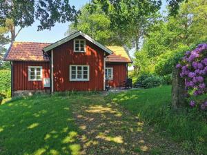 una casa roja en un patio con árboles y flores en Torpet, en Sollebrunn