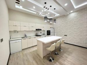 a kitchen with white cabinets and a counter and stools at Villa with a pool & close to the sea in Baku