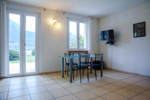 een eetkamer met een tafel, stoelen en ramen bij Villa Oliveto apartments in Oliveto Lario