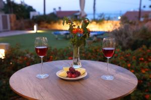 two glasses of wine and a plate of fruit on a table at Chios Shallow Sea in Karfas