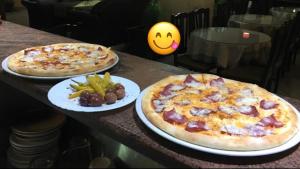 duas pizzas sentadas em pratos numa mesa com comida em E & P Hotel 2 em Tetovo