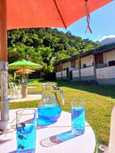 a table with two glasses and a pitcher of water at Chalés Luz Da Lua in Caraguatatuba