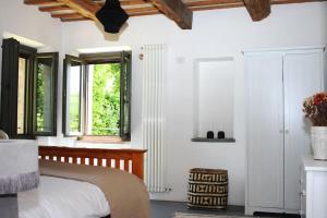 a bedroom with a bed with white walls and windows at Family friendly chic Italian farmhouse with pool in Mogliano