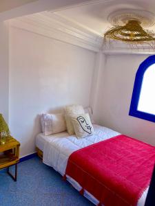 1 dormitorio con 1 cama con manta roja en Oceanside Surf & salsa, en Aourir