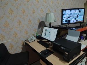 een bureau met een computer, een monitor en een telefoon bij H.V HOTEL BANDARA in Gorontalo