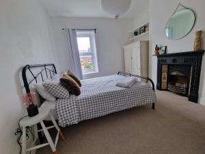 1 dormitorio con 1 cama con chimenea y espejo en Lovely 3 bedroom Whitley Bay Townhouse., en Whitley Bay