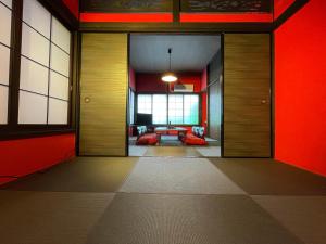 TRAVELERZ YOKOHAMA Demon Slayer House في Kikuna: ممر به جدران حمراء وأبواب مع غرفة معيشة