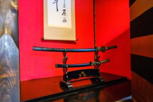 TRAVELERZ YOKOHAMA Demon Slayer House في Kikuna: طاولة مع آلة خياطة قديمة الطراز مقابل جدار احمر
