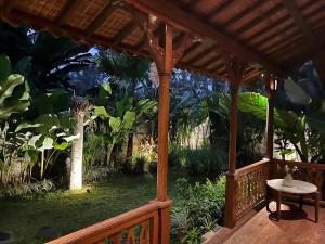 a wooden gazebo with a table in a garden at Kaiwatu House in Ubud