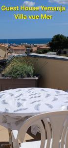 une table blanche et des chaises posées au sommet d'un balcon dans l'établissement Guest House Yemanja, à Narbonne