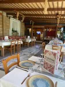 a dining room with tables and chairs with plates and wine glasses at TE BUJTINA HOTEL- Cozy Stay with Traditional Breakfast Near Beach in Golem