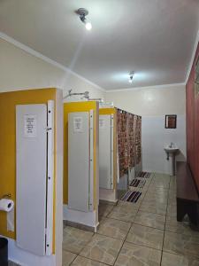 a bathroom with four stalls in a room at Cabana Hostel nas Árvores EcoPark in São Pedro