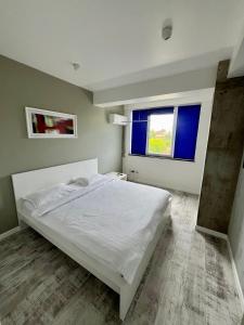 a bedroom with a white bed and two windows at Central Bliss in Suceava