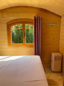 1 dormitorio con 1 cama en una habitación con ventana en Bungalow de 2 chambres avec piscine partagee jardin clos et wifi a Saint Pardoux, en Saint-Pardoux