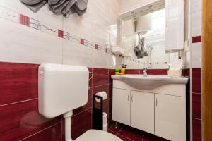 La salle de bains est pourvue de toilettes blanches et d'un lavabo. dans l'établissement Apartments Klaric, à Krilo