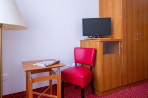a room with a red chair and a television at Logierhaus Extra in Norderney