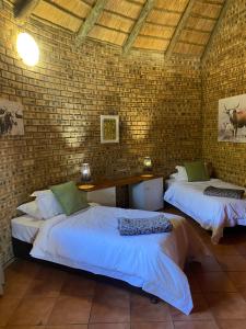 - une chambre avec 2 lits et un mur en briques dans l'établissement Soetgeluk Farm Cottage, à Hekpoort