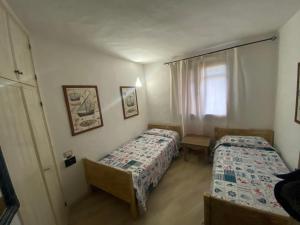 1 dormitorio con 2 camas y ventana en Appartamento Baja Sardinia, en Baja Sardinia