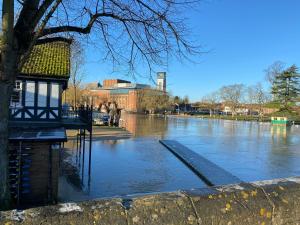a flooded river with a building in the background at Stratford upon Avon: 2 bed town centre apartment, parking for one car in Stratford-upon-Avon