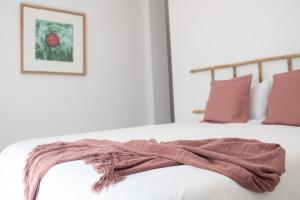 une couverture sur le bord d'un lit avec des oreillers roses dans l'établissement Comfortable Centric Apartment Steps from the Beach, à Gran Tarajal