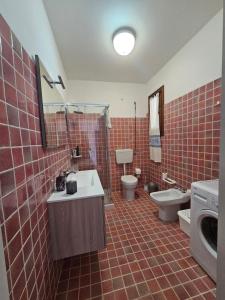 ein rot gefliestes Bad mit einem Waschbecken und einem WC in der Unterkunft Casa La Pelosa in Stintino