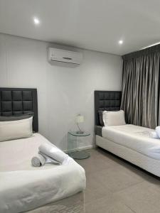 a bedroom with two beds and a table in it at Two Bedroom at Pebble Beach in Umhlanga +15 photos