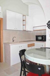 una cucina bianca con tavolo e forno a microonde di Casa Bruni 104 a Putignano