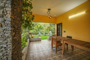 a dining room with a wooden table and a stone wall at Rain Rock Villa in Yercaud