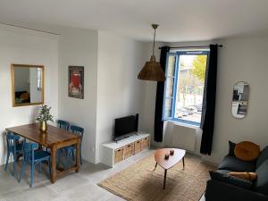 uma sala de estar com uma mesa de jantar e uma televisão em Le Jules Appart'Hotel em Romans-sur-Isère
